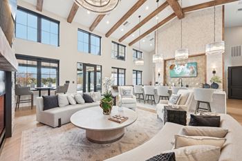 A large, well-lit living room with a variety of seating options and a central coffee table.at The Garrison Luxury Apartment Homes, Fountain, CO 80817